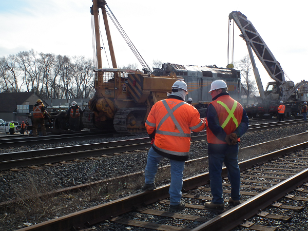 Un employé du CN et un enquêteur observent le redressement d'un wagon de train
