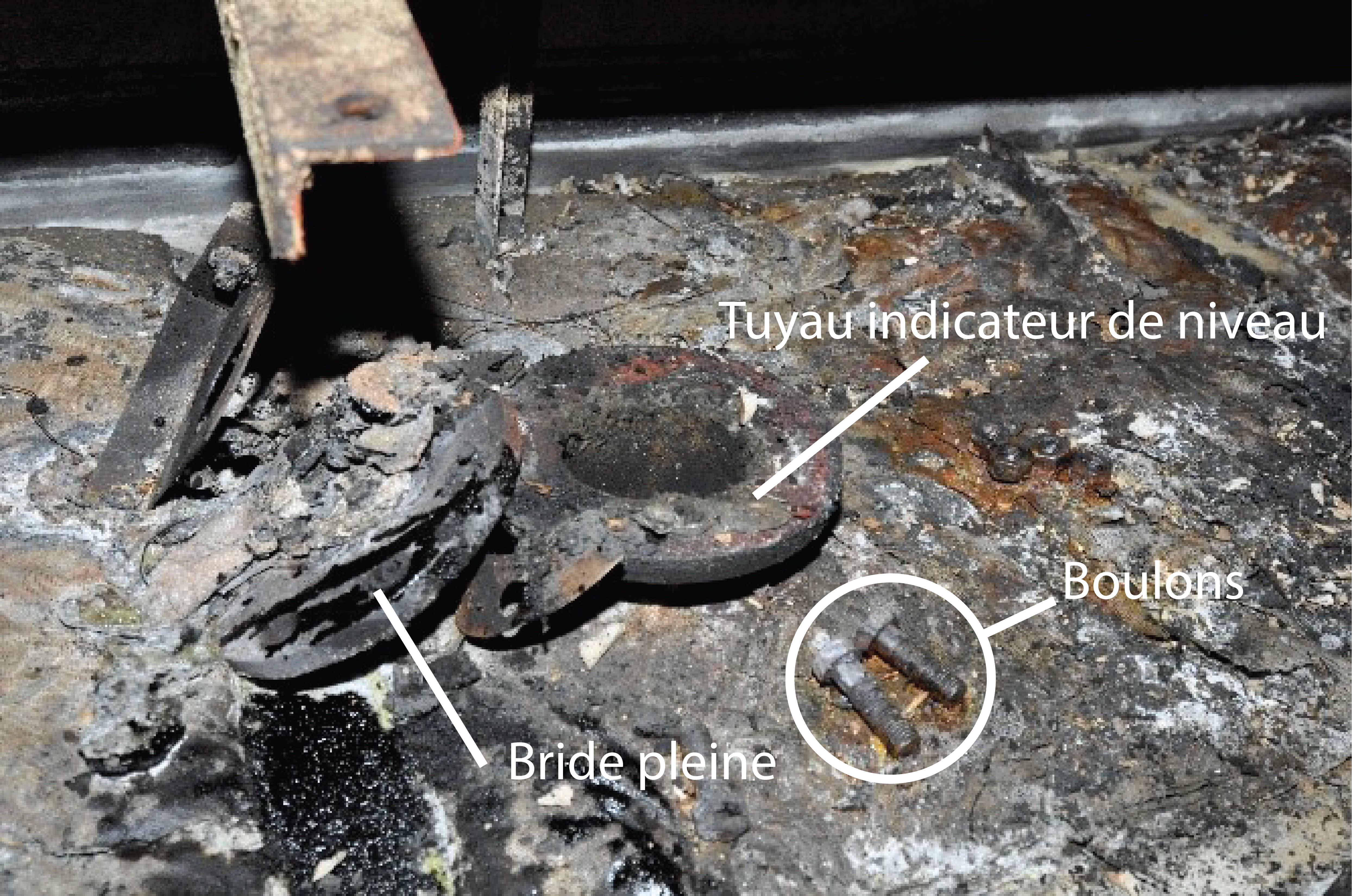 L’ouverture du tuyau indicateur de niveau, ainsi que la bride pleine, des écrous et des boulons, sur le dessus de la caisse de décantation, après l’incendie (Source : BST)